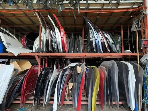 Organized racks of car doors, hoods, and body panels in storage