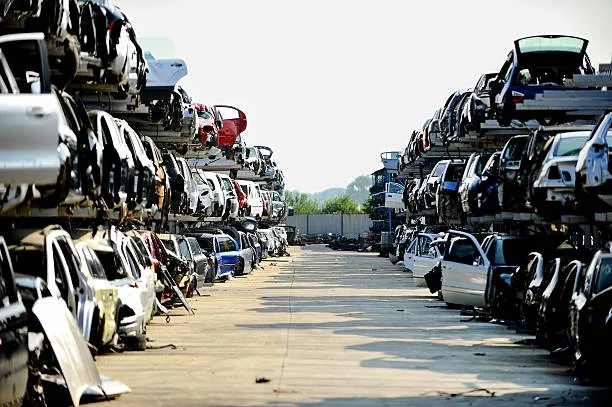 Salvage yard with stacked vehicle bodies and spare parts inventory